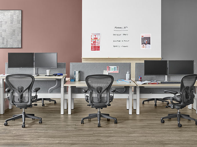 Well lit workspace with a two piece Renew Link and individual desk positioned against the wall with three Aeron chairs behind each work surface
